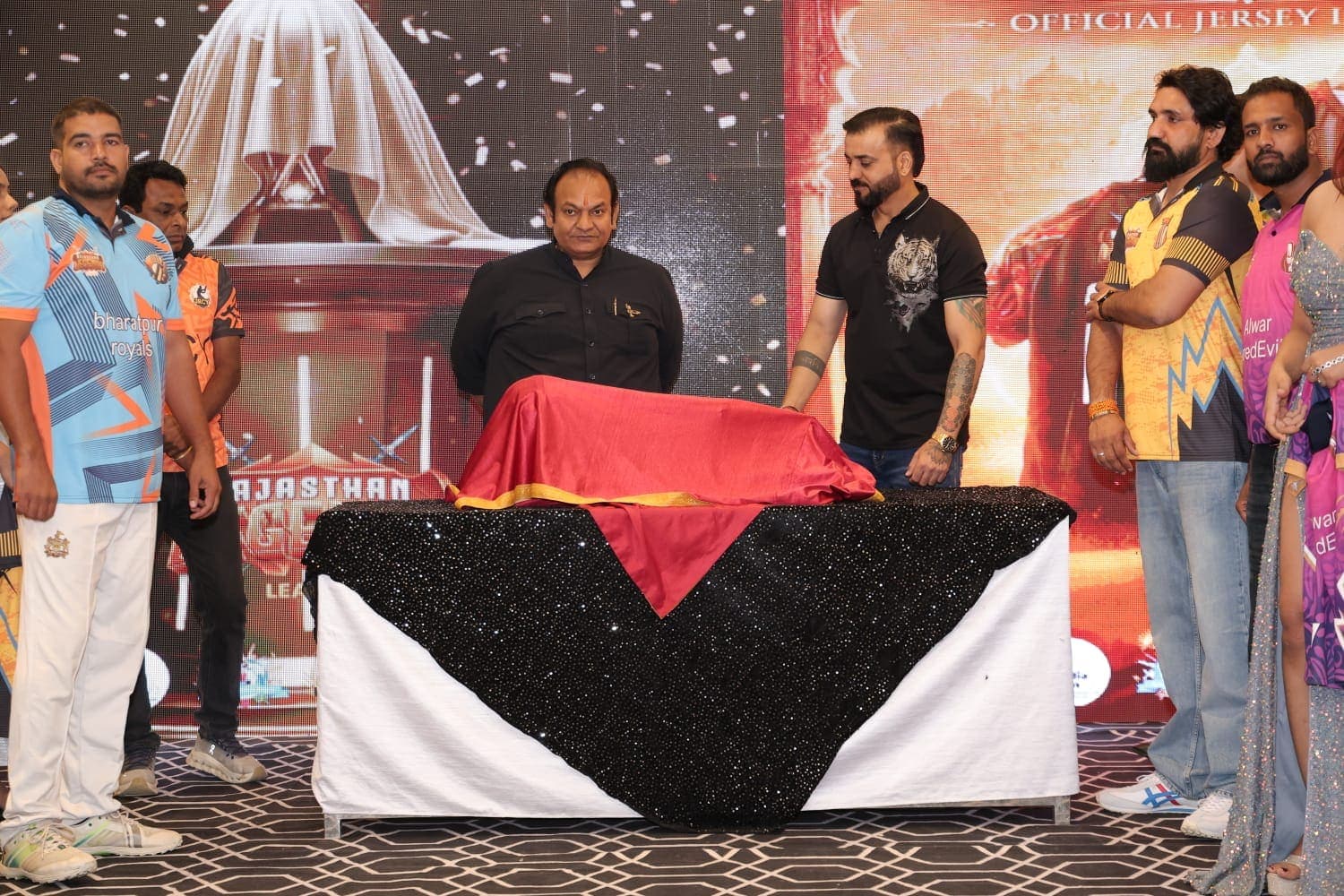 Trophy unveiling on stage at a franchise jersey launch.